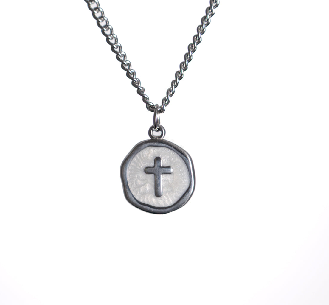 Silver necklace with a round pendant featuring a cross on a white background