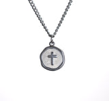 Silver necklace with a round pendant featuring a cross on a white background