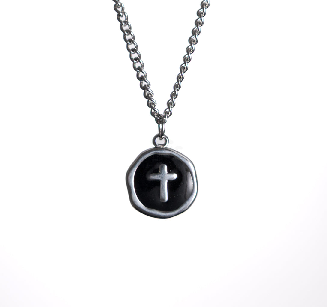 Necklace with a black pendant featuring a silver cross on a white background