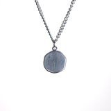 Silver necklace with a round pendant on a white background