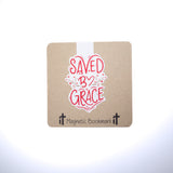 Double sided magnetic bookmark featuring red hand lettered text reading Saved by Grace with floral accents on a kraft style background, designed for Christian reading and Bible study