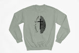A sage green crewneck sweatshirt with a black graphic on the chest featuring a split fingerprint design, a cross, and the cursive text 'Created in His Image'.